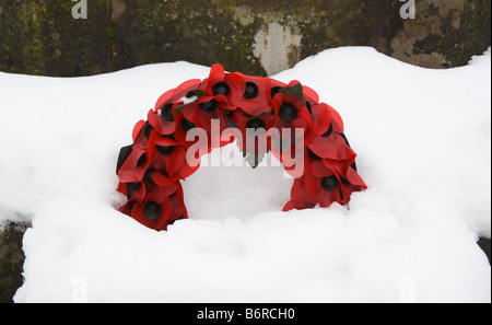 Kranz künstlicher Mohn auf einem schneebedeckten Kriegsdenkmal, Großbritannien Stockfoto