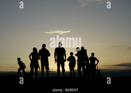 Silhouette von einer Gruppe von Menschen auf einem Hügel bei Sonnenuntergang. Stockfoto