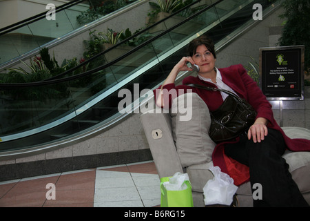 Frau ruht während des Gesprächs auf Handy in einem Einkaufszentrum in New York. Stockfoto