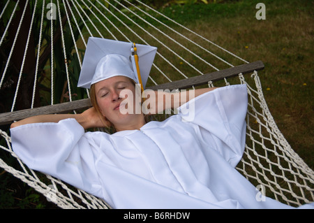 Graduate Mädchen in einen Doktorhut liegen in der Hängematte Stockfoto