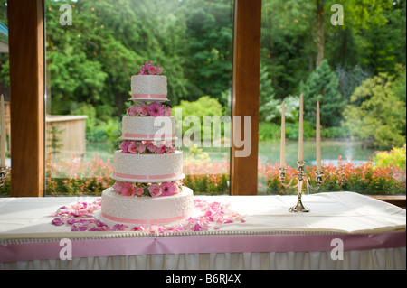 Rosenblätter verstreut eine Multi Tier Hochzeitstorte durch ein Fenster mit Aussicht Stockfoto