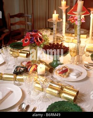 Nahaufnahme der Tabelle für Weihnachtsessen mit gold Cracker und beleuchtete Kerzen mit Geschirr und Besteck Stockfoto
