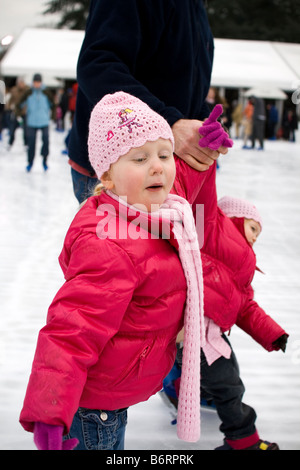 Ein Mann hält seine zwei kleinen Kinder beim Lernen zu skaten. Stockfoto