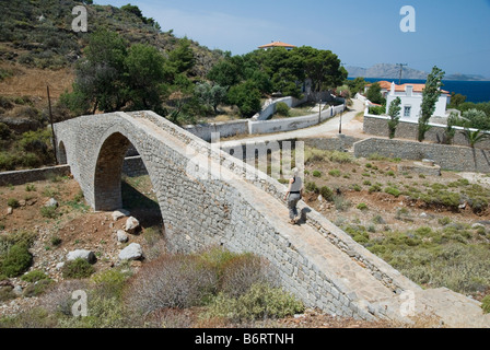 Eine touristische Wanderungen über ein restauriertes Gebäude aus dem 19. Jahrhundert steinerne Brücke in der hübschen Stadt Vlyhos auf Hydra, Griechenland Stockfoto