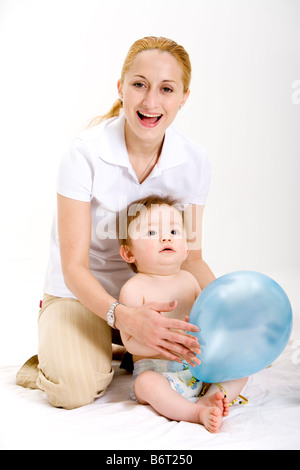 Mutter mit Baby sitzen auf dem Boden berühren Ballon-Porträt Stockfoto