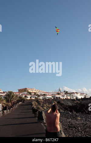 Eine junge fliegt einen Drachen in einem klaren blauen Himmel an der Küste in Playa San Juan-Teneriffa-Kanarische Inseln-Spanien Stockfoto