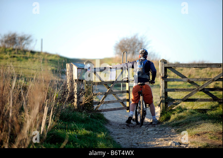 Ein Radfahrer geht durch ein Tor auf der South Downs im Ditchling Beacon in Sussex UK Stockfoto