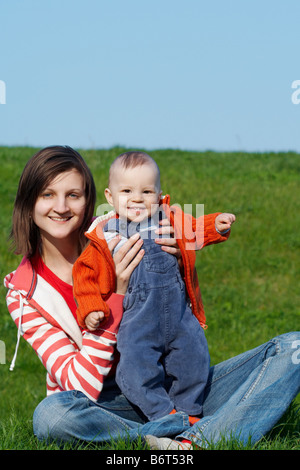 Glückliche Mutter mit Sohn sitzen auf dem grünen Rasen Stockfoto