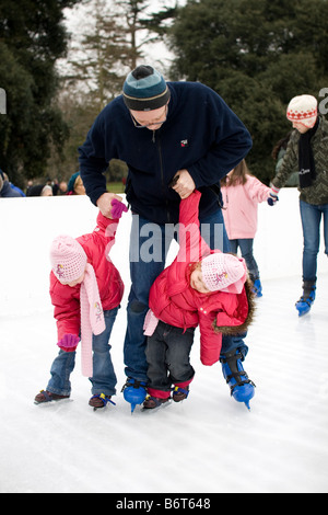 Ein Mann hält seine zwei kleinen Kinder beim Lernen zu skaten. Stockfoto