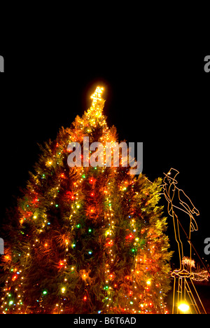 Weihnachtsbaum Lichter in der Nacht Figur in alte altmodische Kleidung und Hut im Dunkel der Nacht Stockfoto