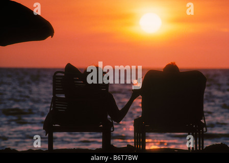 Paar in Strand Lounge Stühle teilen tropischen Drink bei Sonnenuntergang Kaunaoa Strand Mauna Kea Beach Hotel Kohala Küste Insel von Hawaii Stockfoto