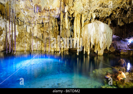 VALLADOLID, Mexiko – einheimische und besuchende Schwimmer genießen das kristallklare Wasser von Cenote X'kakah in der Nähe von Valladolid, Yucatan. Das natürliche Kalkstein-Schwimmloch verfügt über dramatische Stalaktiten, die von der Decke hängen und durch eine kleine Öffnung darüber natürliches Licht erhalten. Dieser unterirdische Pool ist Teil des riesigen Netzes unterirdischer Wasserstraßen unter der Halbinsel Yucatan. Stockfoto