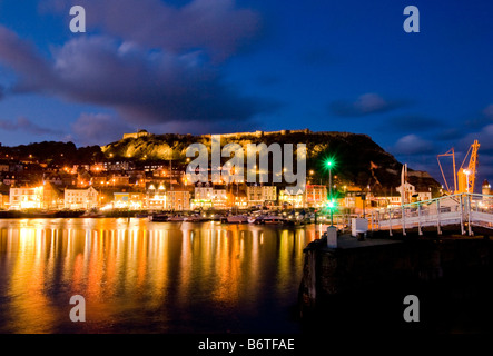 Abend-Blick über Hafen in Richtung Scarborough Castle vom Leuchtturm Pier zeigt beleuchtete Spiegelungen im Wasser Stockfoto