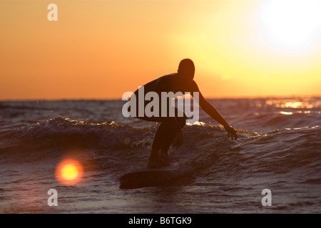 Surfer reiten in auf kleine Welle bei Sonnenuntergang am Lake Michigan Stockfoto