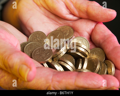 Junger Mann streckte beide Hände mit Pfund-Münzen in beiden Händen Stockfoto