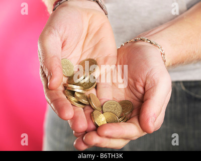 Junger Mann streckte beide Hände mit Pfund-Münzen in beiden Händen Stockfoto