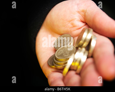 Junge Person, die Hand voll von Pfund-Münzen Stockfoto