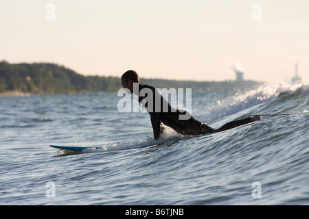 Surfer im Lake Michigan klettert an Bord um Welle zu erwischen Stockfoto