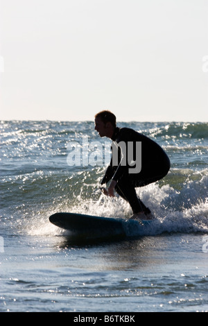 Surfer immer niedrig für eine Fahrt auf einer Welle im Lake Michigan Stockfoto