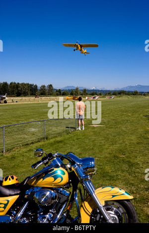 Mann beobachtet eine gelbe Piper Cub Aircraft Corporation bei Piper Cub Fly-in Snohomish Washington USA ausziehen Stockfoto