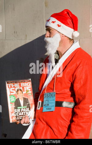 Ein Obdachloser Mann verkleidet als Weihnachtsmann, Verkauf von the Big Issue Magazin in London UK Stockfoto