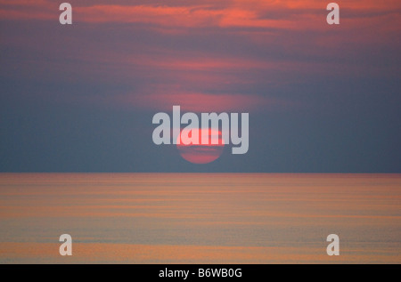 GROßE ROTE SONNE AM MEER MIT WOLKEN EINSTELLUNG Stockfoto