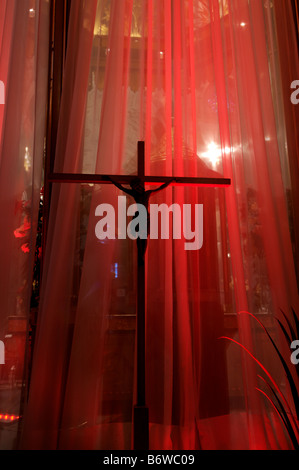 Eine Statue von Jesus am Kreuz gegen einen roten Vorhang in einer Kirche Stockfoto