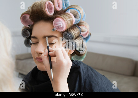 Modell in Lockenwickler mit Make-up angewendet Stockfoto