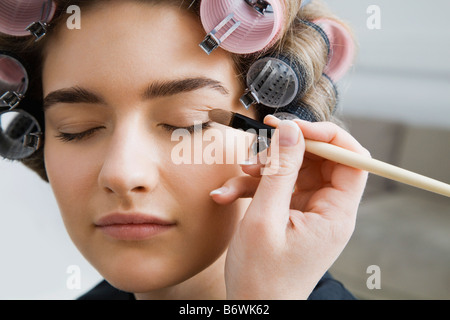 Modell in Lockenwickler mit Make-up angewendet Stockfoto