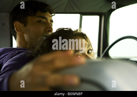 Mann sitzt mit Arm um Freundin im Auto am Strand Stockfoto