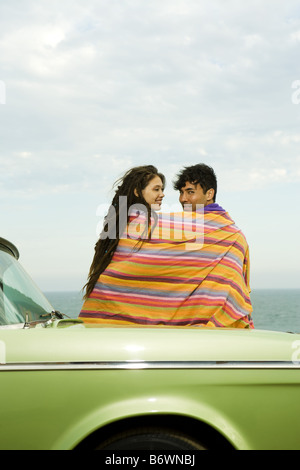 paar in Decke am Strand mit Oldtimer gewickelt Stockfoto