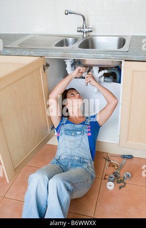 Eine junge Frau, die ein Waschbecken reparieren Stockfoto