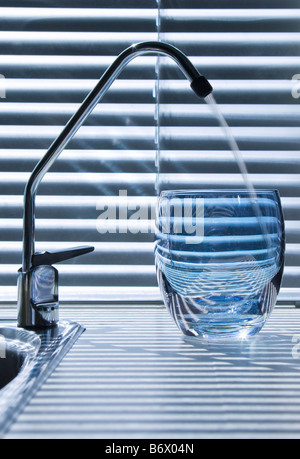 Gefiltertes Wasser in ein Glas von einem unter Waschbecken Wasserfilter-System mit dem Wasserhahn an der Seite einer Küchenspüle. Stockfoto