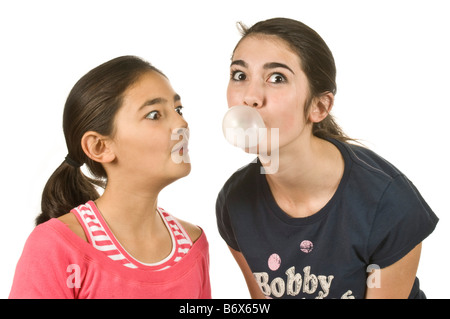 2 Mädchen (11 und 14) mit einem weht eine große bubblegum Blase und die anderen schauen erstaunt mit reinem weiß (255) Hintergrund. Stockfoto