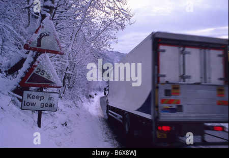 LKW Reisen durch Winterschnee vorbei Warnzeichen der steilen Hügel am Sutton Bank in der Nähe von Thirsk Yorkshire UK Stockfoto