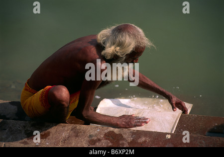 Indien, Varanasi, alter indischer Mann, der Kleidung im Ganges-Wasser wäscht Stockfoto