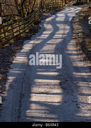 Winterliche zaun Schatten wiggly Muster auf eisigen Straßen in Cumbria GROSSBRITANNIEN Stockfoto