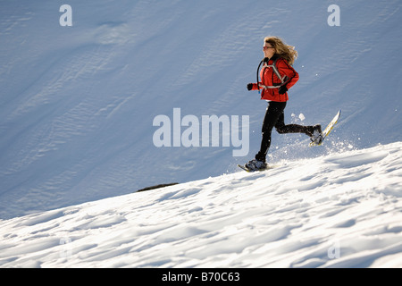 Frau läuft auf Schnee mit Schneeschuhen. Stockfoto