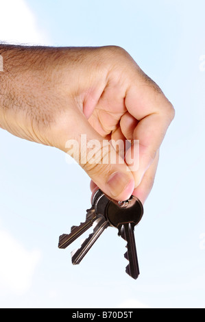 Mann s Hand, die Hausschlüssel auf blauen Himmelshintergrund Stockfoto