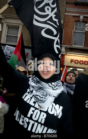 Protest gegen die Bombardierung des Gazastreifens vor der israelischen Botschaft. Junge Frau gekleidet in schwarz wehende Flagge mit arabische Schrift Stockfoto