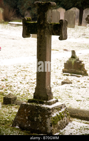 Ein Steinkreuz in keltischer Knoten in einem verschneiten Friedhof schnitzen bedeckt Stockfoto