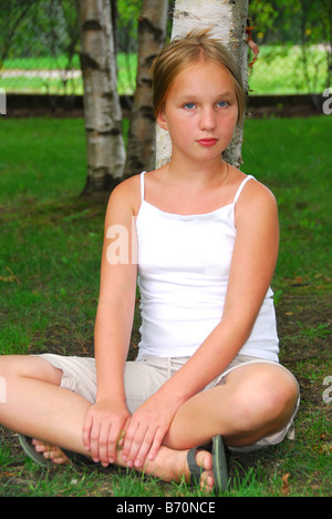 Porträt von einem jungen hübschen Mädchen sitzen unter einer Birke in einem park Stockfoto