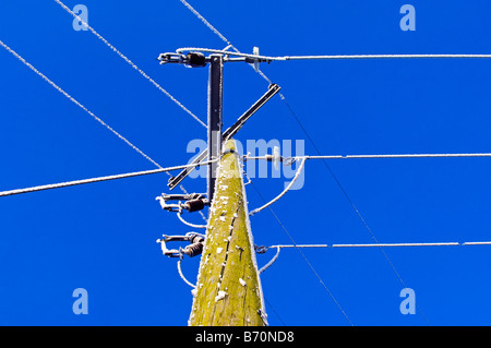 Stromkabel und Stromkabel gegen blauen Himmel eingefroren Stockfoto