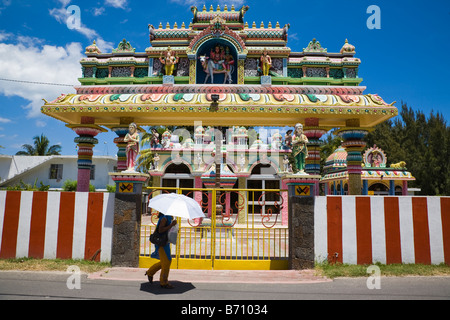 Die Außenseite des Hindu Tempel in der Nähe von Grand Baie in Mauritius mit einer Frau zu Fuß durch die Zuflucht unter einem Dach - von der starken Sonneneinstrahlung Stockfoto