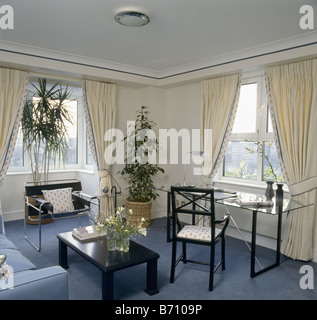 Tisch mit Glasplatte und Marcel Breuer Wassily Chair in Wohnung Wohnzimmer mit blauen Teppich und cremefarbene Vorhänge Stockfoto