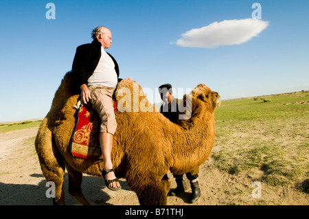 Ein Reisender genießt eine Fahrt auf einem doppelten Buckel baktrischen Kamel im großen mongolischen Grasland. Stockfoto