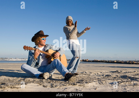 Junge interracial Pärchen am Strand Gitarre spielen und tanzen Stockfoto
