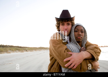 Interracial Pärchen stehen am Strand mit Arm um Stockfoto