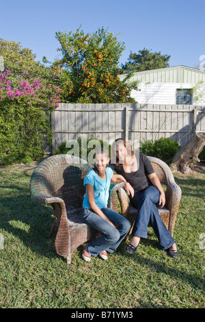 Glücklich afroamerikanische Mutter und Tochter sitzen auf Hof im freien Stockfoto