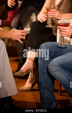 Niedrige Schnittansicht von jungen Erwachsenen sitzen, die Getränke und hängen zusammen Stockfoto
